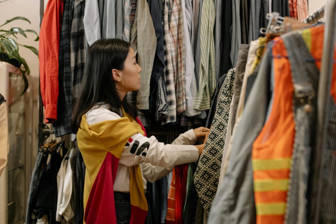 A colorful second-hand clothing market, with people browsing racks of clothes.
